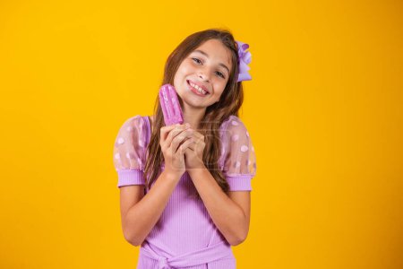 Photo for Small caucasian girl with delicious grape popsicle smiling looking at camera. Summer - Royalty Free Image