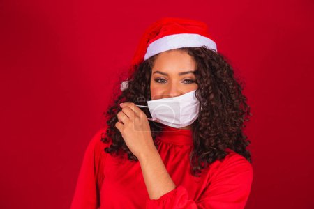 Photo for End of the pandemic at Christmas. Woman taking off her mask with Santa Claus hat - Royalty Free Image