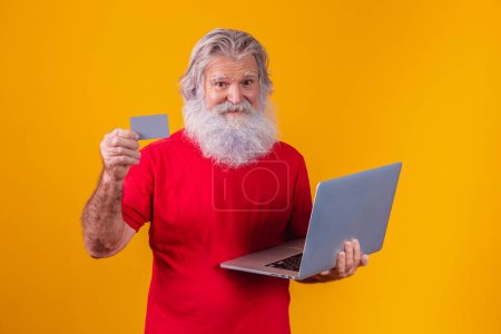 Téléchargez les photos : Homme âgé tenant un ordinateur portable et une carte de crédit bancaire. transaction d'achat en ligne. Méthode bancaire mobile sans espèces. - en image libre de droit