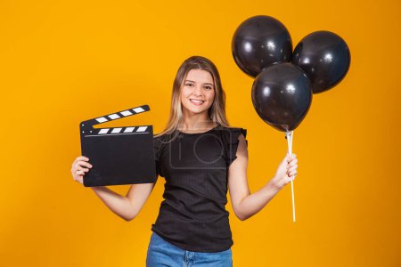 Photo for Young woman holding an audio-visual clapper board and black balloons during Black Friday. Promotion concept. Black Friday - Royalty Free Image