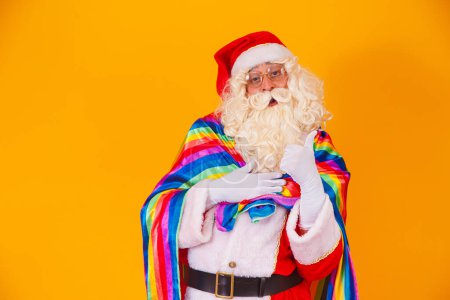 Téléchargez les photos : Père Noël gay tenant le drapeau LGBT. Noel Gay Pride concept.Gay Père Noël sur fond jaune. Père Noël est gay - en image libre de droit