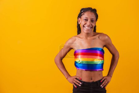 Photo for Young woman covering with lgbt pride flag. Alone. One. Keeping fist up, covering LGBT flag. LGBT+ flag on yellow background. - Royalty Free Image