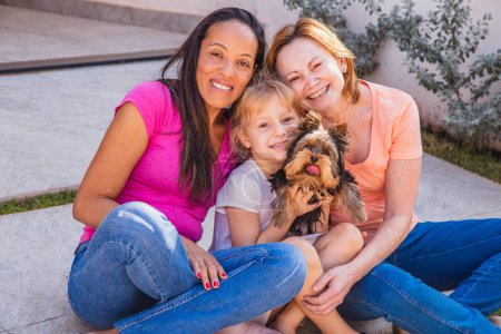 Photo for Smiling lesbian couple with child and pet puppy. Lesbian couple holding with their adoptive daughter, adoption concept. - Royalty Free Image