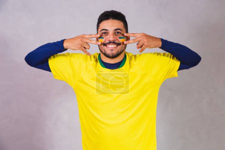 Photo for Brazilian fan. using paint as makeup, Brazilian fan celebrating football or soccer game on grey background. Colors of Brazil. - Royalty Free Image