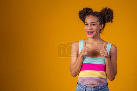 Téléchargez les photos : Portrait de sourire belle jeune fille afro pouces vers le haut. Brésilienne fille. - en image libre de droit