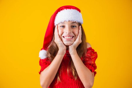 Photo for Portrait of a  caucasian smiling girl in a Santa hat on a yellow background. Christmas and happines concept. Close up, copy space - Royalty Free Image