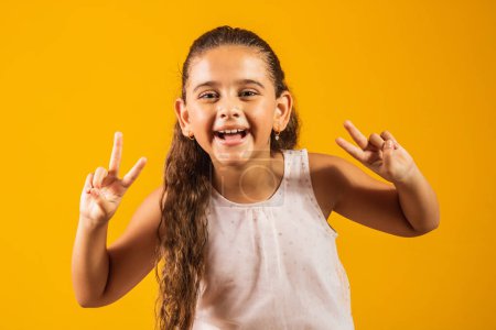 Photo for Adorable little girl making v sign on yellow background. good vibe peace and love - Royalty Free Image