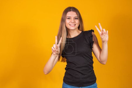 Photo for Image of happy young man standing isolated over yellow background showing peace gesture. Camera looking. - Royalty Free Image