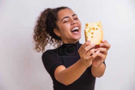 Téléchargez les photos : Jeune femme avec une tranche de fromage à la main. femme mangeant du parmesan. se concentrer sur le fromage - en image libre de droit