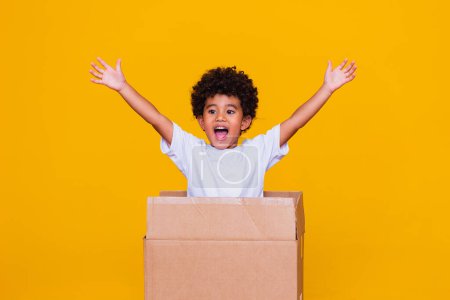 Photo for Small afro boy coming out of cardboard box. - Royalty Free Image