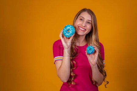 Photo for Portrait of a cheery pretty girl holding blue donuts at her face - Royalty Free Image
