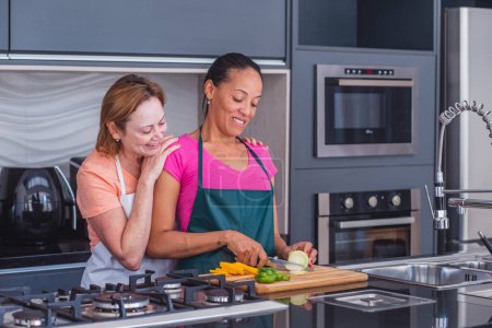 Téléchargez les photos : Lesbienne couple cuisine ensemble dans l'amour - en image libre de droit