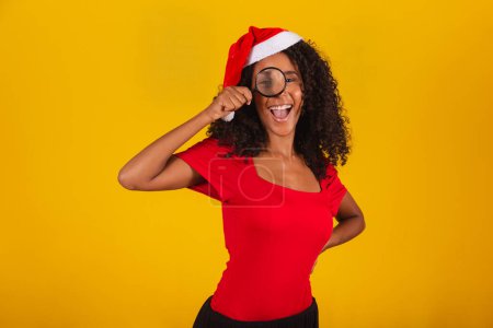 Photo for Woman dressed for christmas in santa hat wearing a magnifying glass - Royalty Free Image