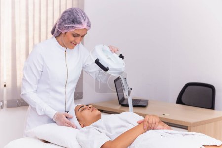 Foto de Mujer en la clínica de belleza haciendo una evaluación facial. Mujer haciendo tratamiento estético - Imagen libre de derechos