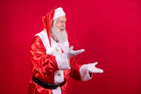 Foto de Santa Claus señalando a un lado, publicidad promoción de Navidad, Año Nuevo publicidad de descuento de Navidad aislado sobre fondo rojo. - Imagen libre de derechos