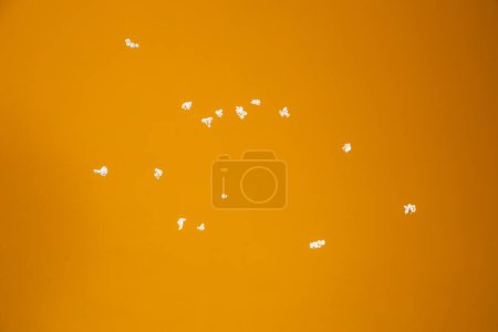Téléchargez les photos : Quelques pop-corn éparpillés sur un fond jaune - en image libre de droit