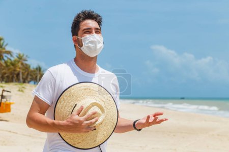 Photo for Close-up of a young man on the beach wearing a mask to protect himself during the pandemic - Royalty Free Image