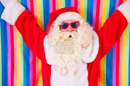 Foto de Gay Santa Claus sosteniendo la bandera LGBT. Concepto del Orgullo Gay de Navidad.Gay Santa Claus sobre fondo amarillo. Papá Noel es gay - Imagen libre de derechos