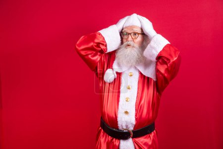 Photo for Forgotten Santa Claus on red background. Santa Claus with his hand on his head like he's forgotten something. Do not remember - Royalty Free Image