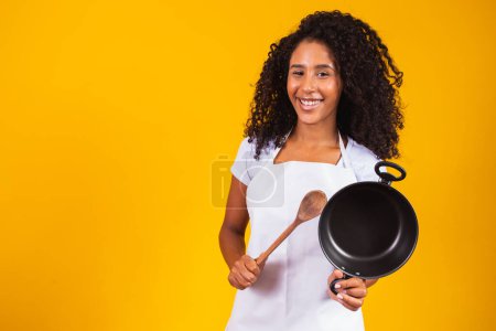 Téléchargez les photos : Des ustensiles de cuisine. Cuisson femme dans la cuisine avec poêle et cuillère en bois. Femme au foyer danse
. - en image libre de droit