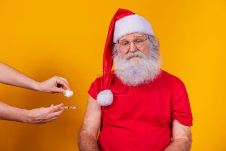 Photo for Santa Claus wearing face mask getting vaccinated with injection - Royalty Free Image