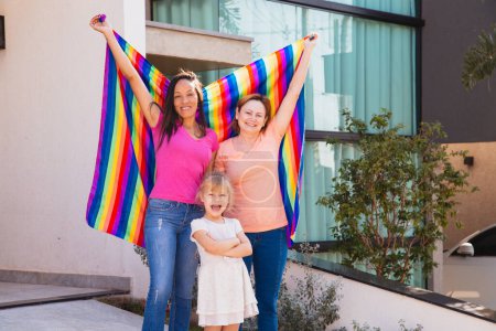 Photo for Smiling lesbian couple with their adopted daughter. gay family with lgbt flag - Royalty Free Image