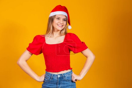 Photo for Positive beautiful blonde woman with Santa hat and red outfit for christmas. Young woman dressed for Christmas smiling. - Royalty Free Image