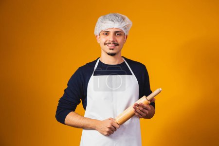 Photo for Young boy pizza maker on yellow background holding rolling pin. - Royalty Free Image