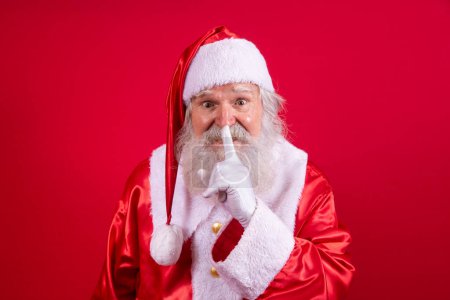 Photo for Santa Claus keeping forefinger by his mouth and looking at camera. Shh! Keep secret. Silent confidential, privacy quiet, shush hissing hush concept. Funny Saint Nicholas. - Royalty Free Image