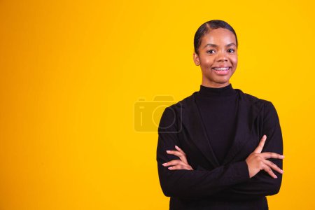 Téléchargez les photos : Femme noire sur fond jaune avec les bras croisés. femme d'affaires sur fond jaune - en image libre de droit