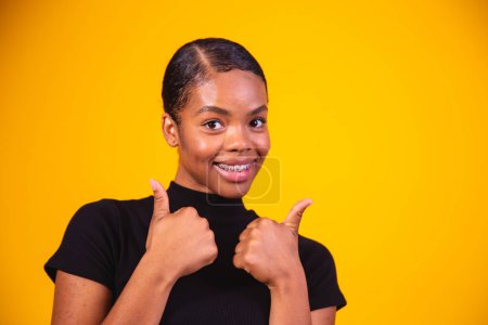 Photo for Black  woman over yellow wall giving a thumbs up gesture because something good has happened - Royalty Free Image