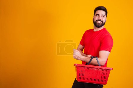 Photo for Handsome caucasian boy holding a shopping basket on yellow background. shopping concept - Royalty Free Image