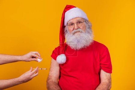 Photo for Santa Claus wearing face mask getting vaccinated with injection - Royalty Free Image