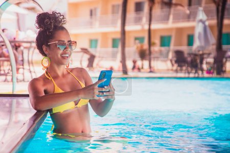 Téléchargez les photos : Femme travaillant par téléphone portable dans la piscine de l'hôtel - en image libre de droit