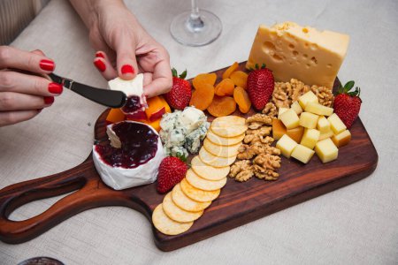 Photo for Hands passing jelly on cheese with various cheeses on the background plate. - Royalty Free Image