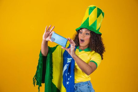 Foto de Partidario de la selección brasileña de fútbol celebrando un gol mirando el smartphone - Imagen libre de derechos
