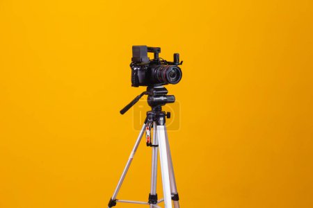 Téléchargez les photos : Trépied caméra cinématographique sur fond jaune - en image libre de droit