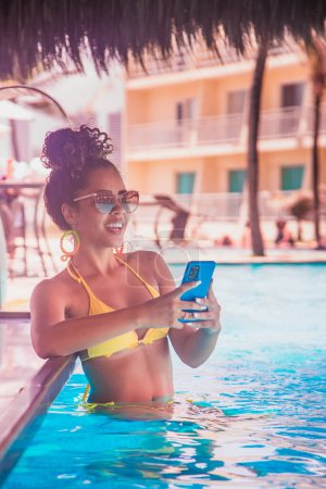Téléchargez les photos : Femme travaillant par téléphone portable dans la piscine de l'hôtel - en image libre de droit