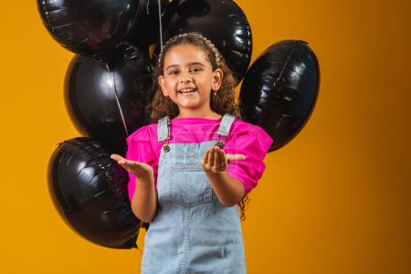 Téléchargez les photos : Petite fille souriante avec des ballons noirs le vendredi noir. festival à bas prix - en image libre de droit