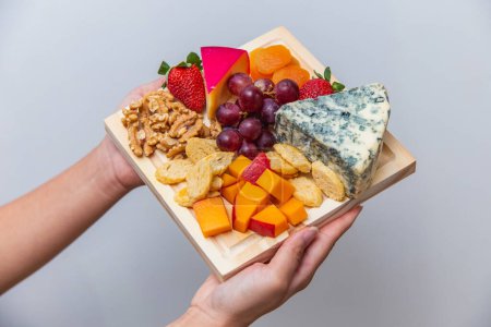 Téléchargez les photos : Main tenant conseil avec divers fromages - en image libre de droit