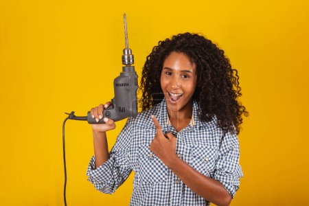 Photo for Contractor woman with a drill smiling at the camera - Royalty Free Image