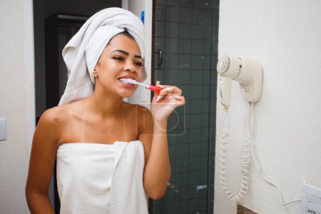 Photo for Afro woman brushing her teeth in the bathroom - Royalty Free Image