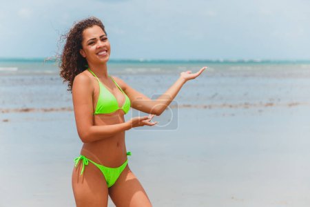 Foto de Hermosa mujer afro brasileña en una playa en rio grande do norte, sonrió, sintiendo la libertad y las olas del mar, disfrutando de sus vacaciones de verano con un maravilloso sol y calidez - Imagen libre de derechos