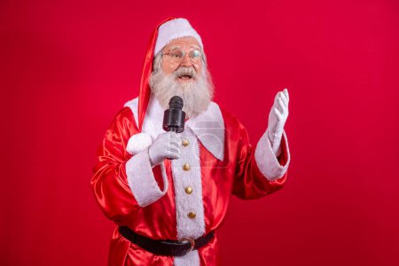 Téléchargez les photos : Père Noël chantant ou parlant dans un microphone de studio. Joyeux Noël. Diffuseur. Annonceur. Promotion. Concept de musique de Noël - en image libre de droit