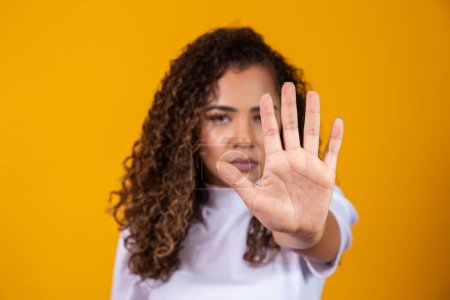 Photo for Close up portrait of a serious young african woman showing stop gesture with her palm isolated - Royalty Free Image