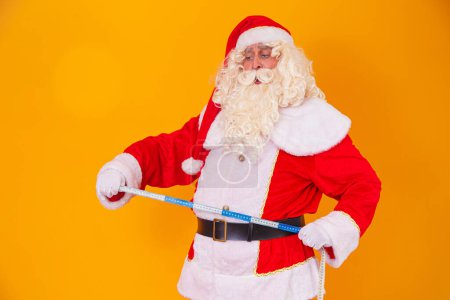 Photo for Santa Claus starting the diet and measuring the belly - Royalty Free Image