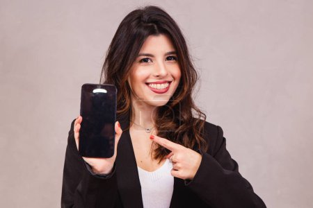 Photo for Portrait of cheerful businesswoman showing cell phone on blank screen isolated over white background. - Royalty Free Image