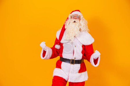 Téléchargez les photos : Père Noël célébrant la victoire en fond jaune - en image libre de droit