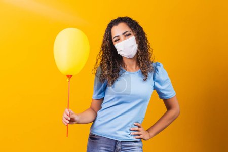 Photo for Young woman with surgical mask holding a yellow balloon. - Royalty Free Image
