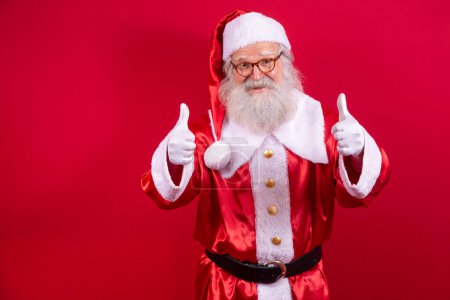 Téléchargez les photos : Père Noël montrant le pouce levé. Père Noël avec une vraie barbe et un grand sourire donnant pouce vers le haut
. - en image libre de droit